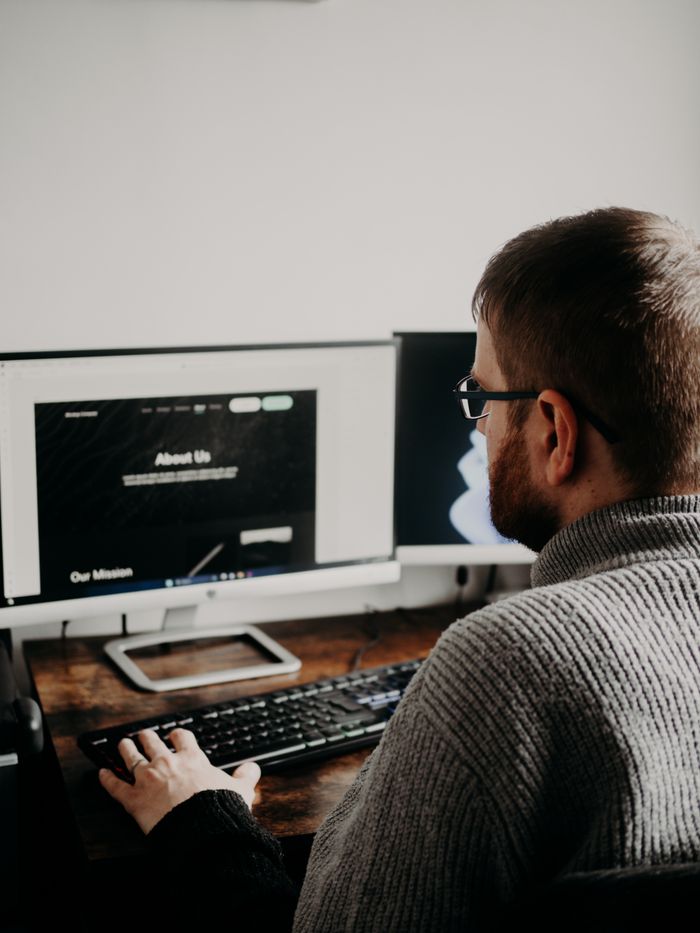 Crafting Captivating Headlines: Your awesome post title goes here Man working on web design at home office setup with dual monitors.