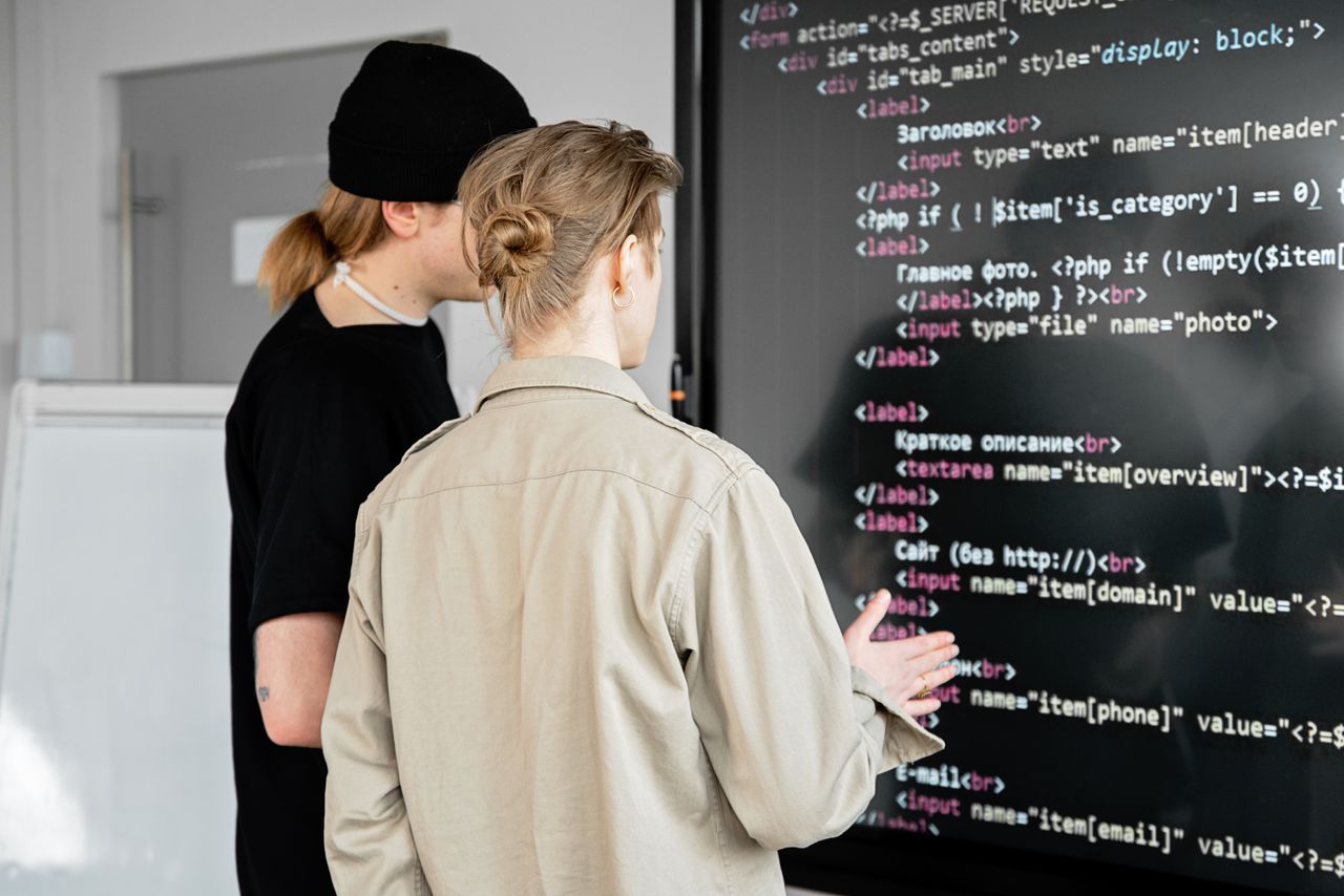 Mastering the First Impression: Your intriguing post title goes here Two developers examining code on a large screen in a modern office space, focusing on web development.